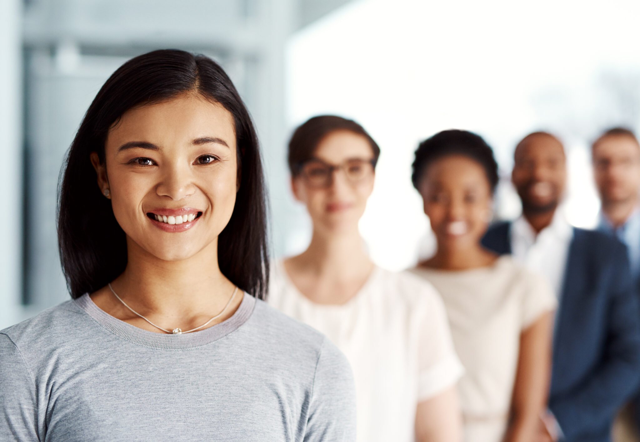 Five office team members lined up diagonally with lady in front smiling