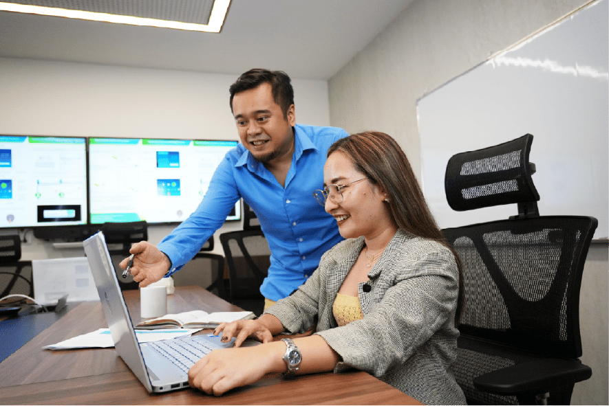 A small group collaborating around a computer workstation in an office setting.