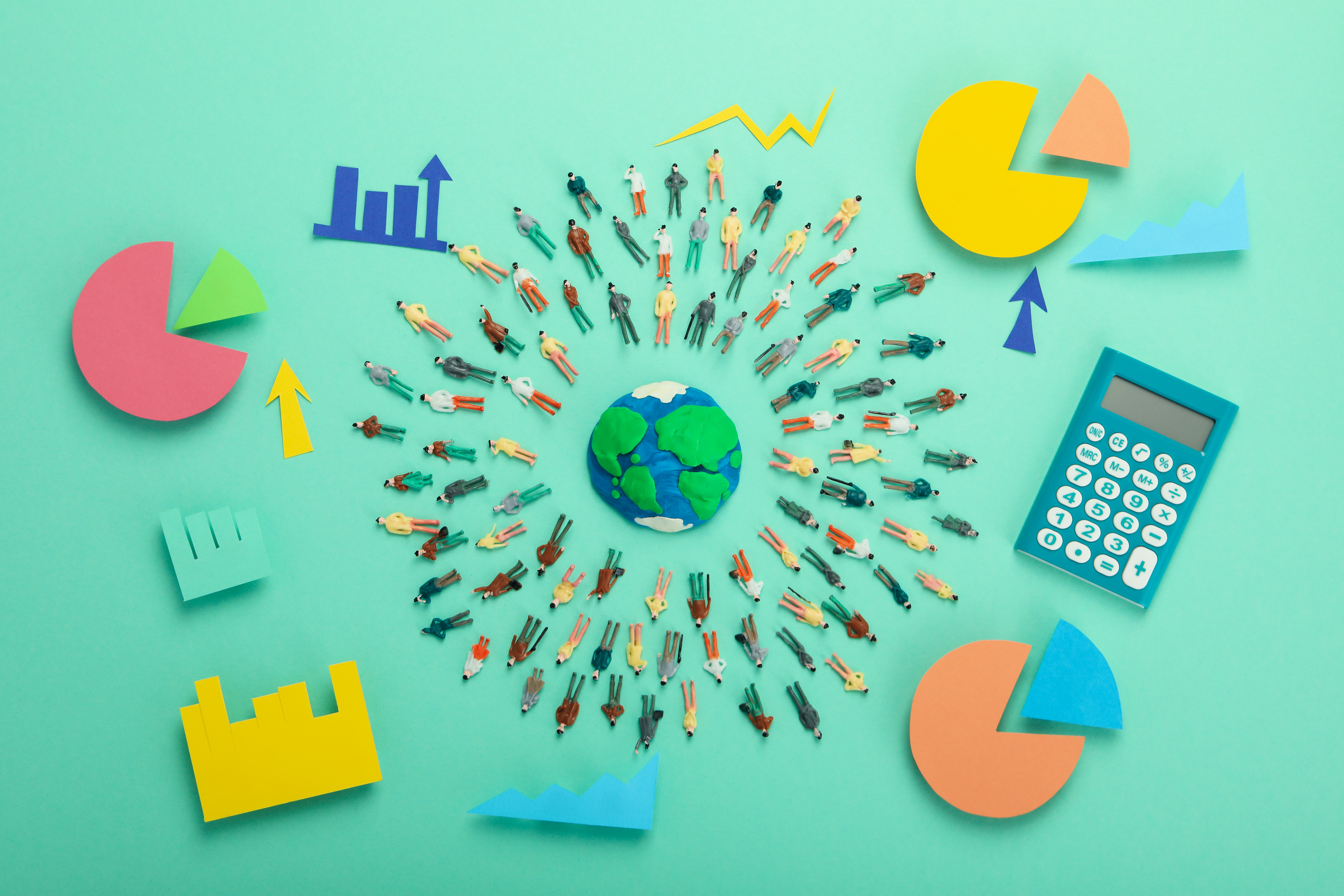 Top view of office supplies arranged strategically to form a globe in the center and human beings surrounding it