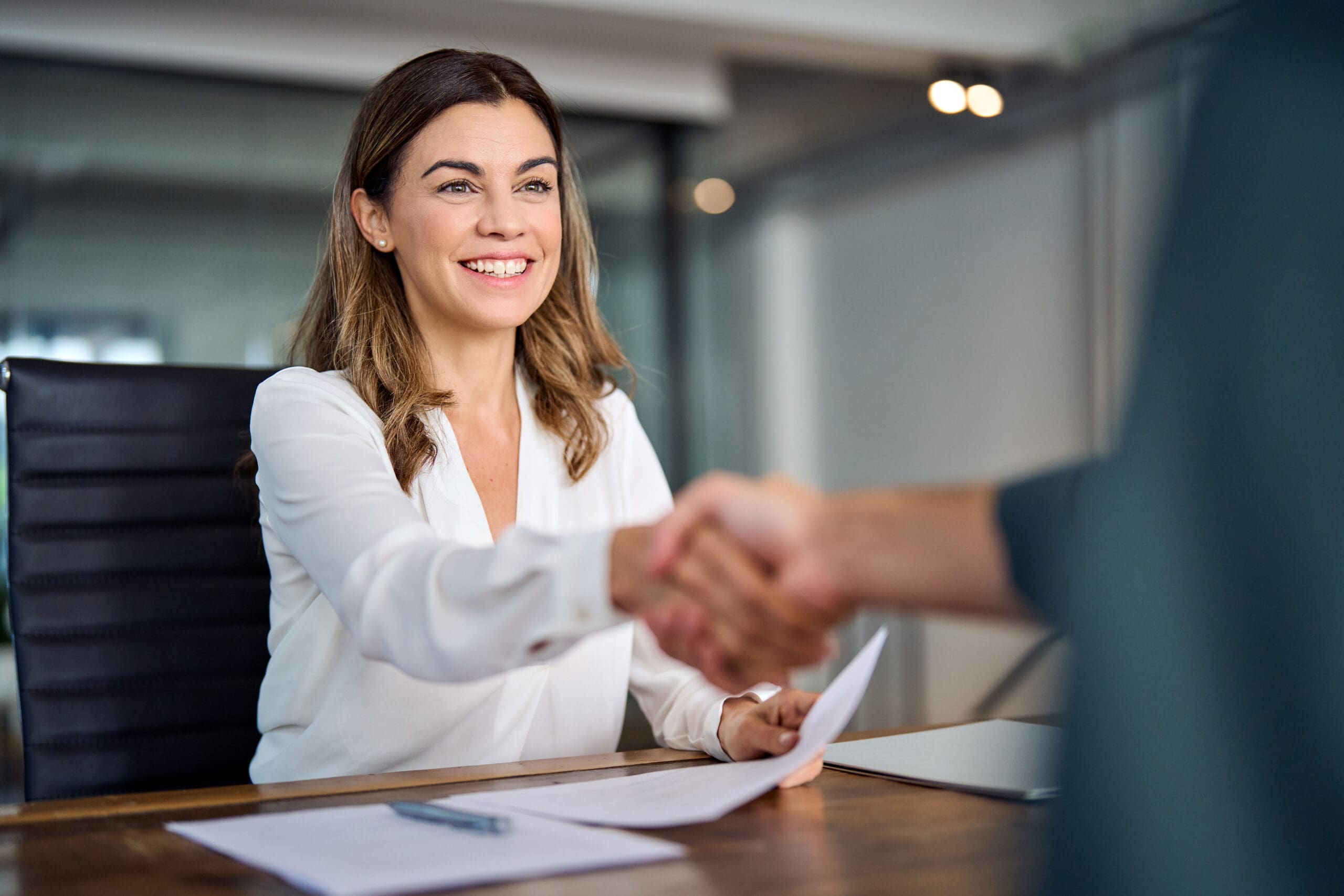 Happy mid aged business woman manager handshaking at office meeting