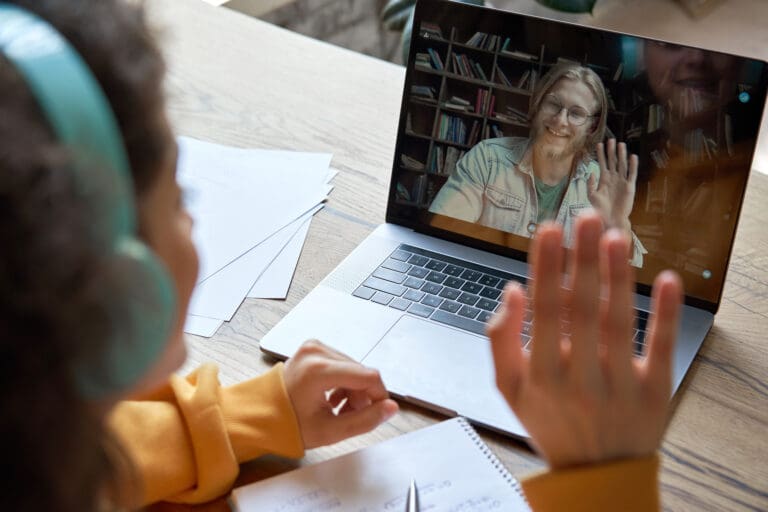Hispanic teen girl distance learning with online teacher on laptop screen